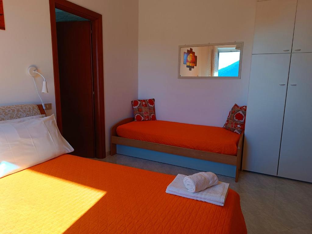 a bedroom with two beds with orange sheets and a mirror at La Roccia Incantata Amalfi Coast in Vietri sul Mare