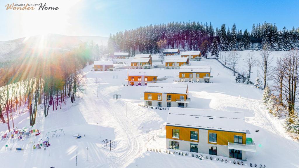 Eine Gruppe von Gebäuden im Schnee, die Sonne scheint in der Unterkunft Wonder Home Myśliwska - Domki przy stoku Karpatka - na terenie kompleksu plac zabaw, zewnętrzna siłownia i sklep in Karpacz