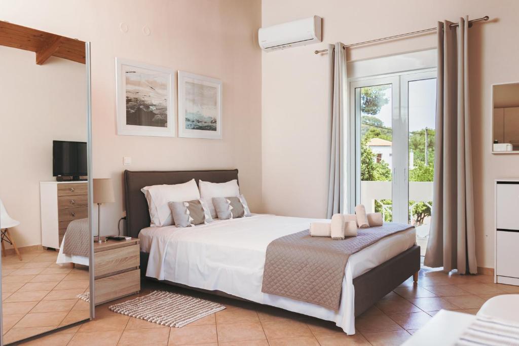 a bedroom with a large white bed and a window at Plakoures Home in Kounoupidhianá