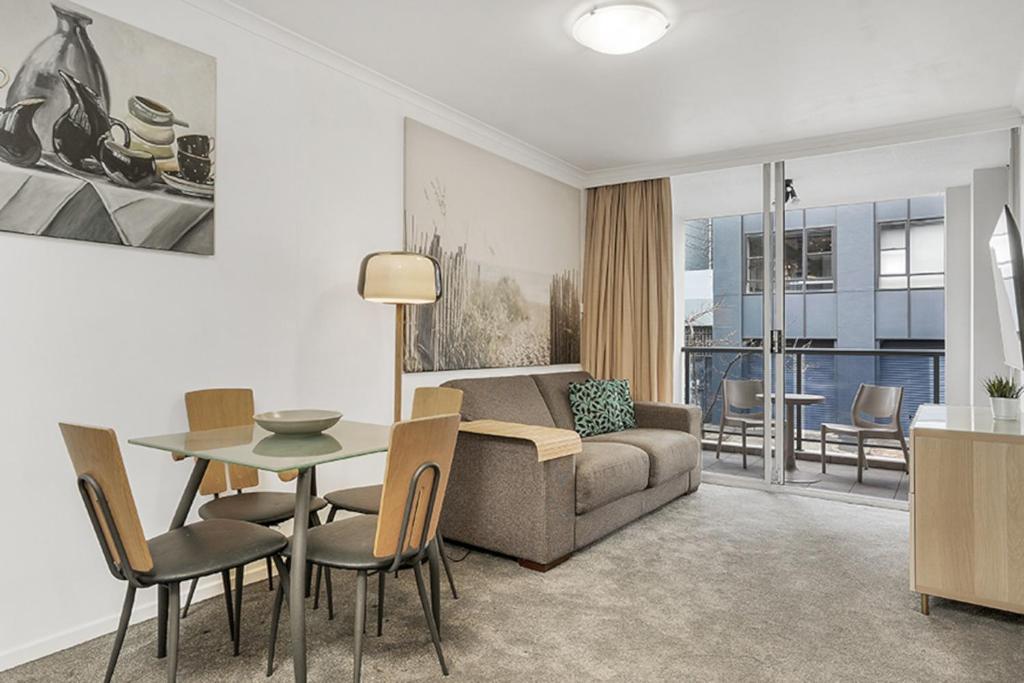 - un salon avec un canapé, une table et des chaises dans l'établissement Contemporary Apartment, à Sydney