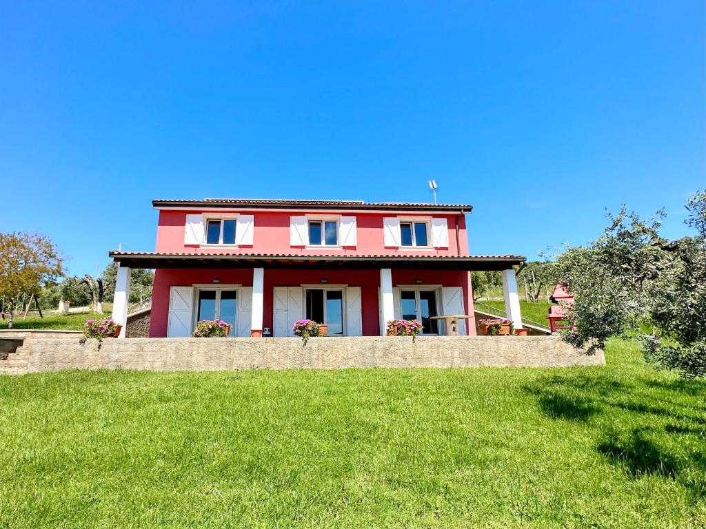 ein rotes Haus auf einem grünen Feld in der Unterkunft Villa San Bartolo in San Vincenzo