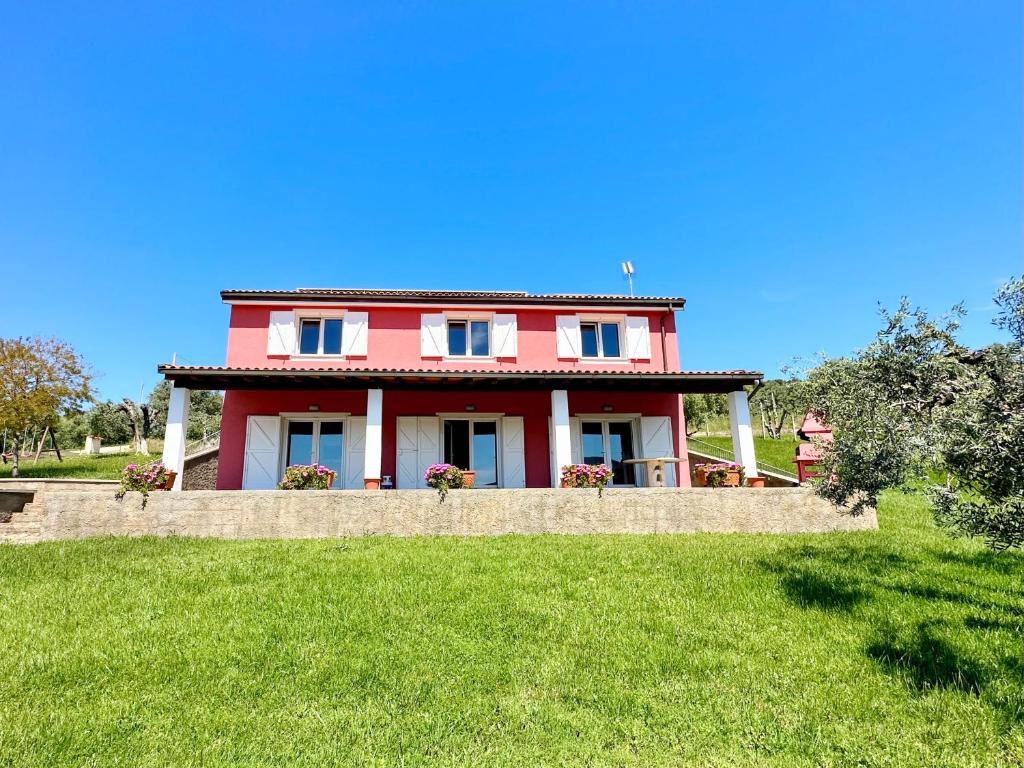 a red house on top of a green field at Villa San Bartolo in San Vincenzo