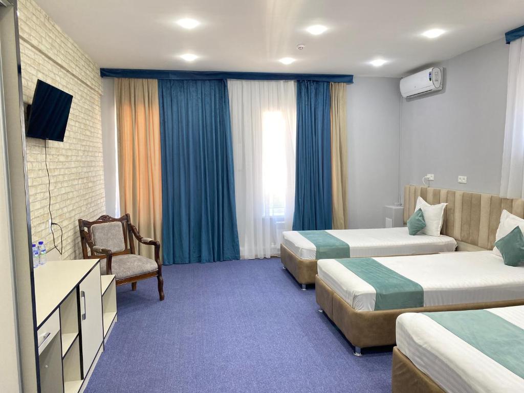 a hotel room with two beds and a chair at Aperol Hotel in Tashkent