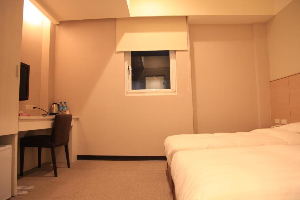 a hotel room with two beds and a desk and a window at Royal Hotel in Taipei