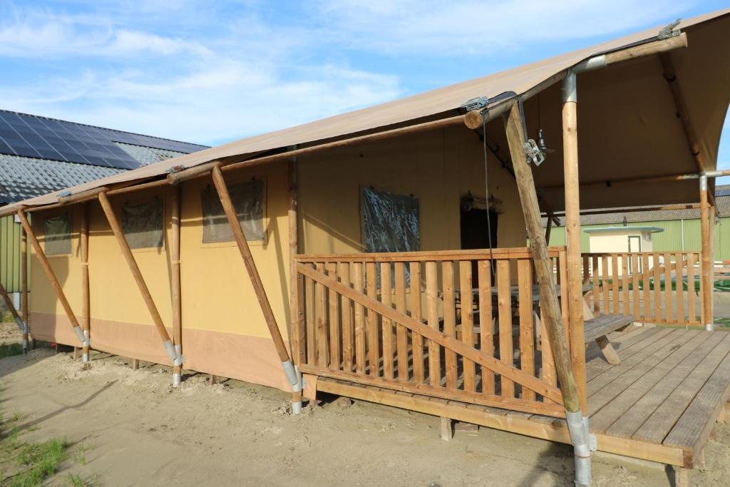 een huis met een terras met een zonnedak bij De Zuidvliet Glamping Deluxe 1 in Wolphaartsdijk