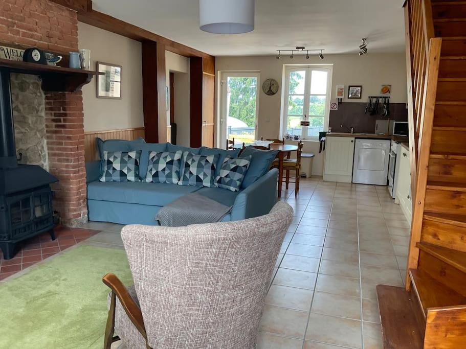 ein Wohnzimmer mit einem blauen Sofa und einer Küche in der Unterkunft La Petite Maison in Saint-Dizier-Leyrenne