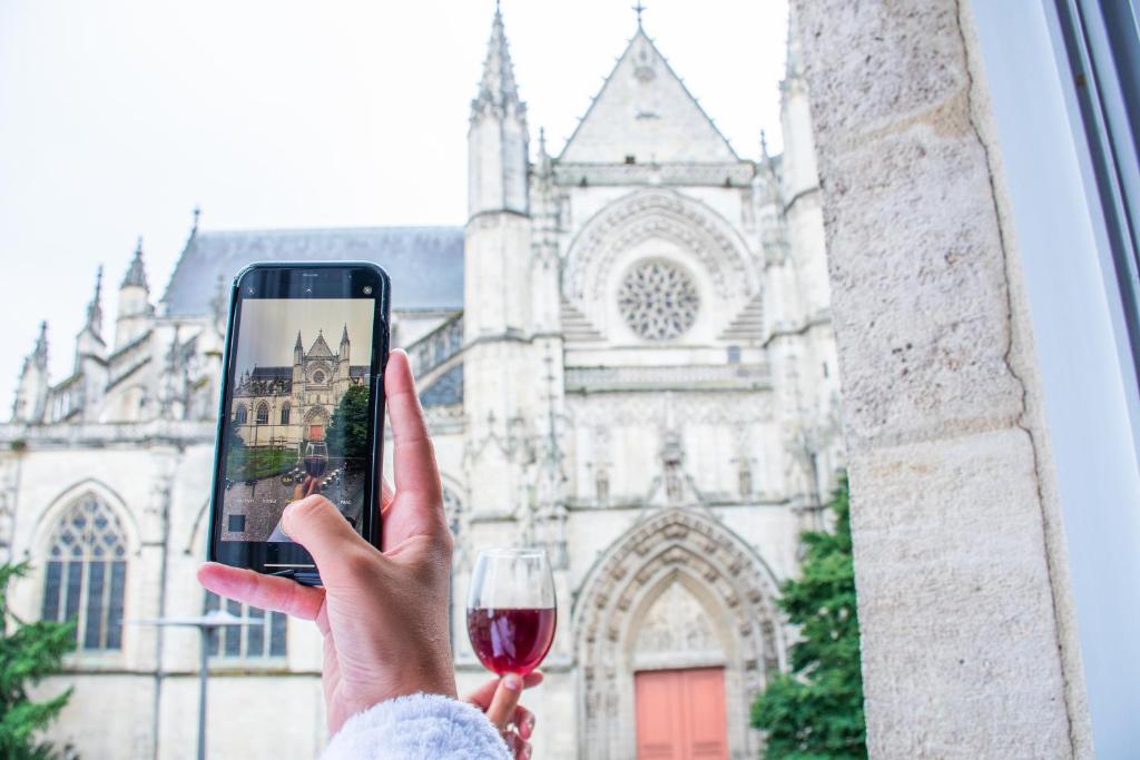 a person taking a picture of a church with a glass of wine at LOLA Boutique Hôtel - Bordeaux Centre in Bordeaux