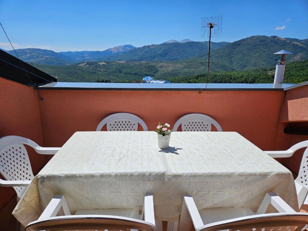 een witte tafel met stoelen en een vaas met bloemen op een balkon bij Quiete del Sirino in Moliterno