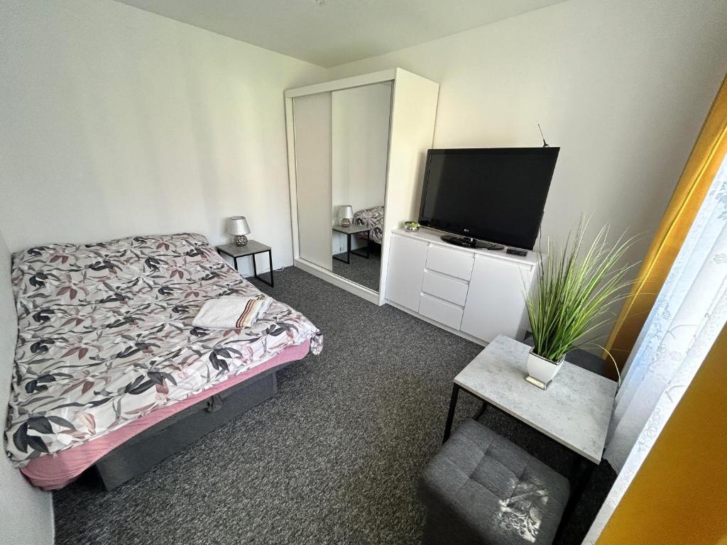 a bedroom with a bed and a flat screen tv at Apartament in Orzysz