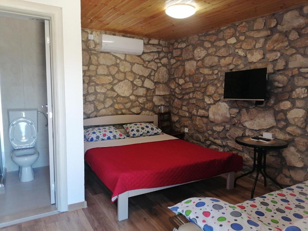 a bedroom with a bed and a tv in a stone wall at Apartmani Perosevic in Danilovgrad