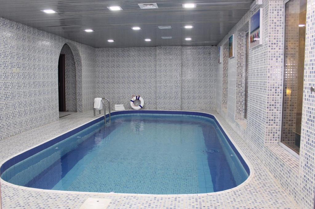 een grote blauwe badkuip in een badkamer met witte tegels bij البستان للأجنحة الفندقية in Al Hofuf