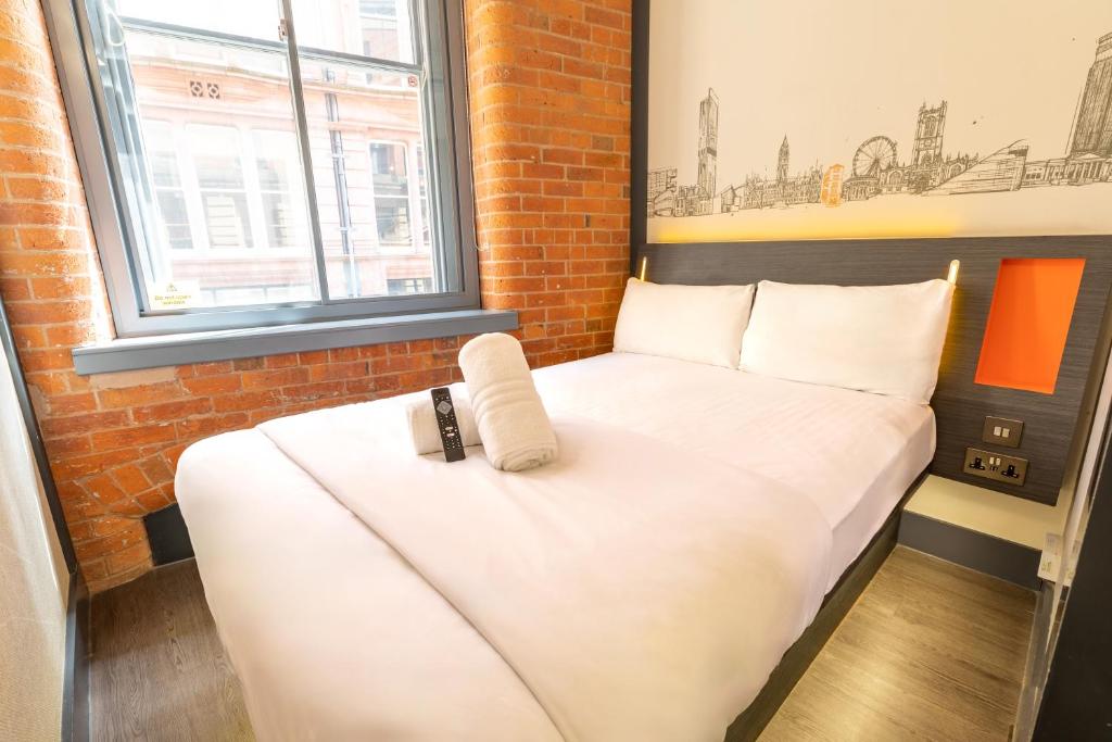 een slaapkamer met een bed met een afstandsbediening bij easyHotel Manchester in Manchester