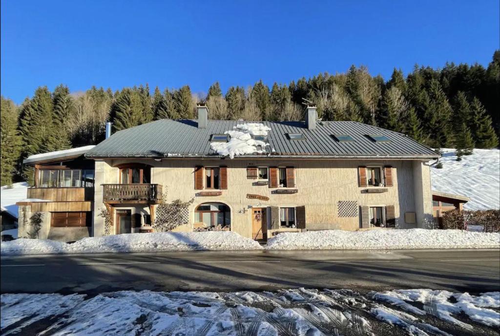 a large house with snow on the front of it at Gîtes Sous Les Loges in Lélex