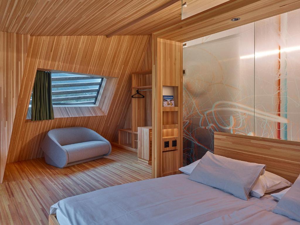 een slaapkamer met een bed, een stoel en een raam bij Hotel Glocke in Reckingen - Gluringen