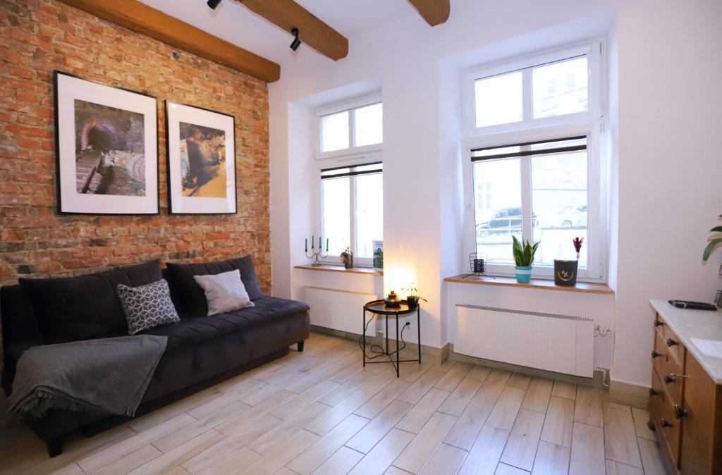 a living room with a couch and a brick wall at Apartament Gwarek in Wałbrzych