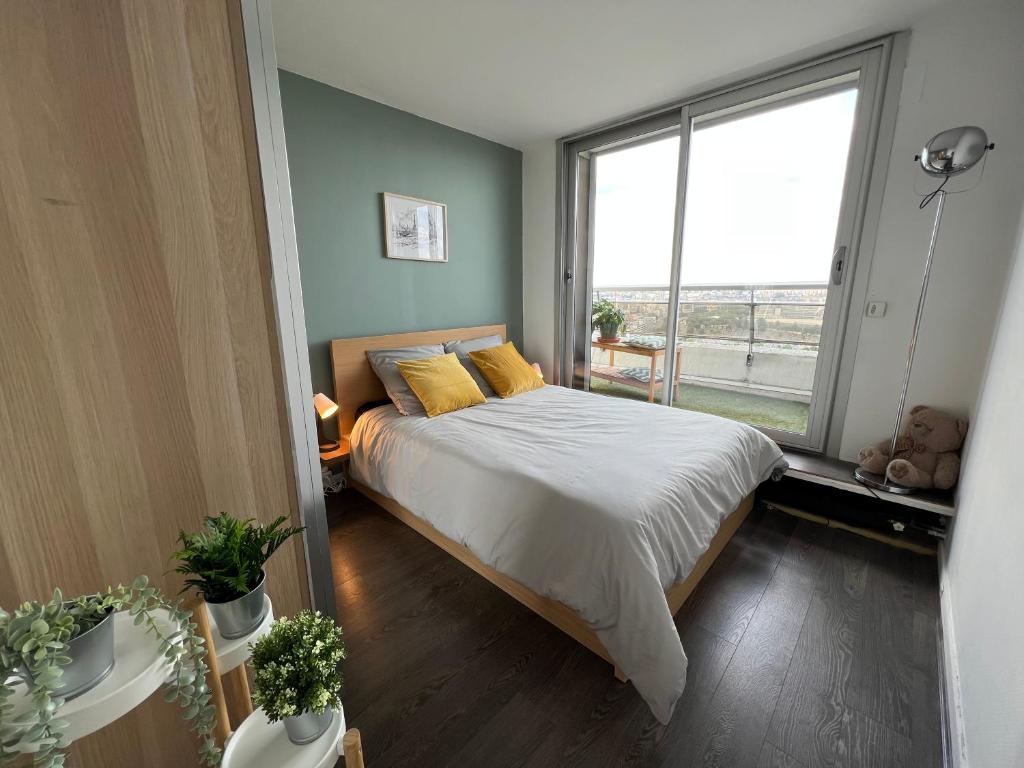 une chambre avec un lit et une grande fenêtre dans l'établissement Above Paris Eiffel Tower view Balcony, à Paris