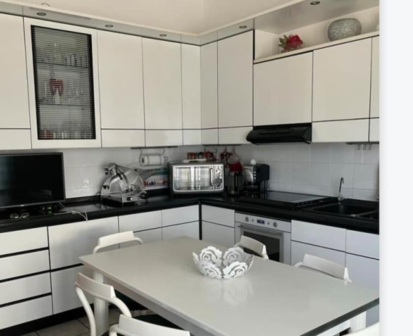 uma cozinha com armários brancos e uma mesa e cadeiras brancas em A casa di Gianni em Gallarate
