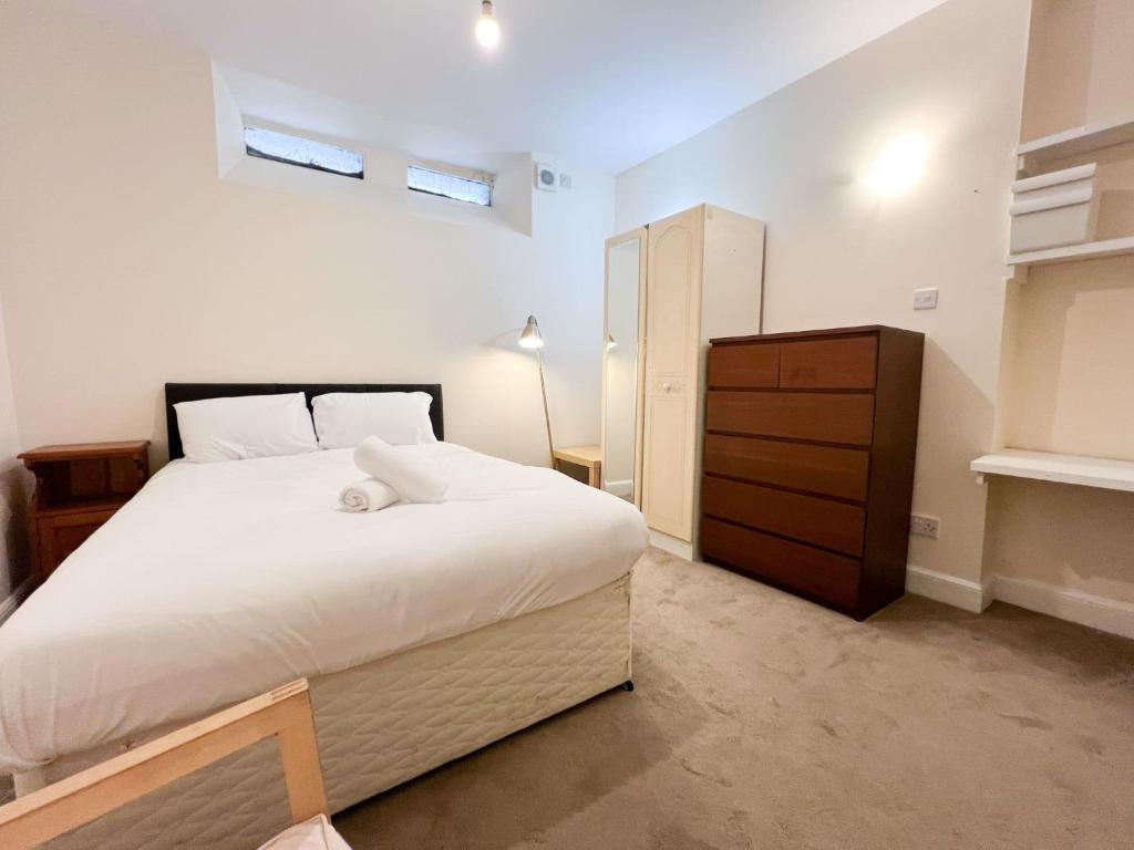 ein Schlafzimmer mit einem großen weißen Bett und einer Kommode in der Unterkunft Convenient 2BR Basement Flat in Leith in Edinburgh