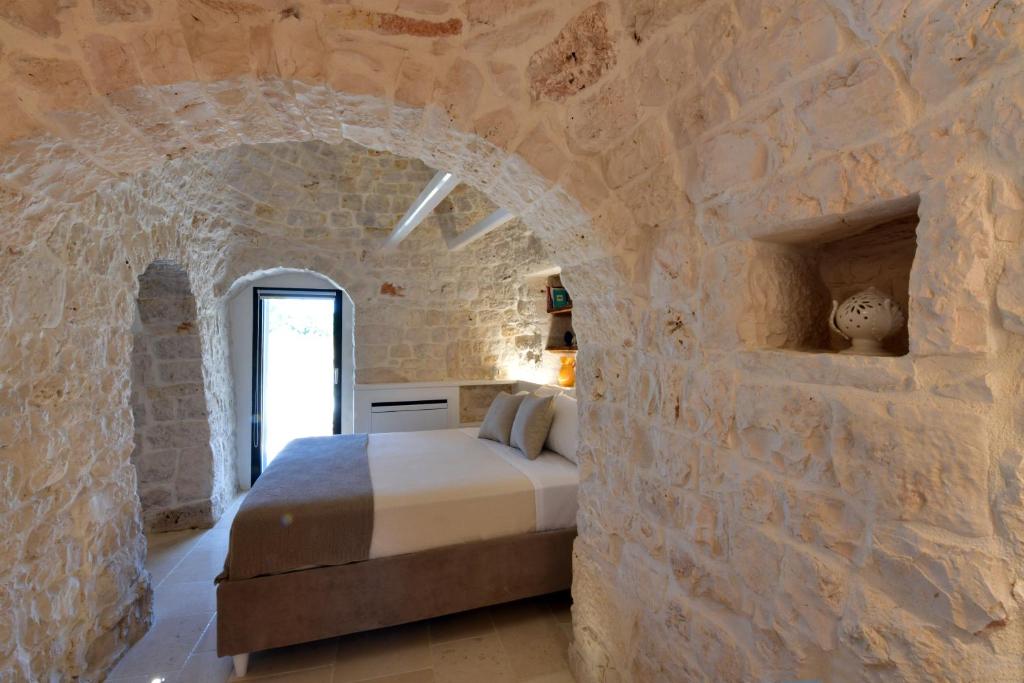 - une chambre avec un lit dans un mur en pierre dans l'établissement Trulli di Titti - Country House, à Castellana Grotte