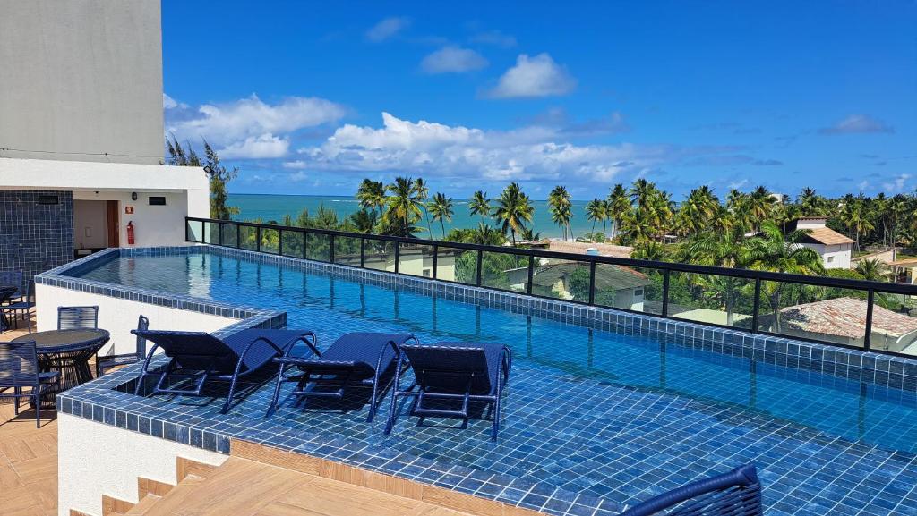 uma piscina com cadeiras e vista para o oceano em Apartamento com piscina no Condominio Maraca2 em Ipojuca