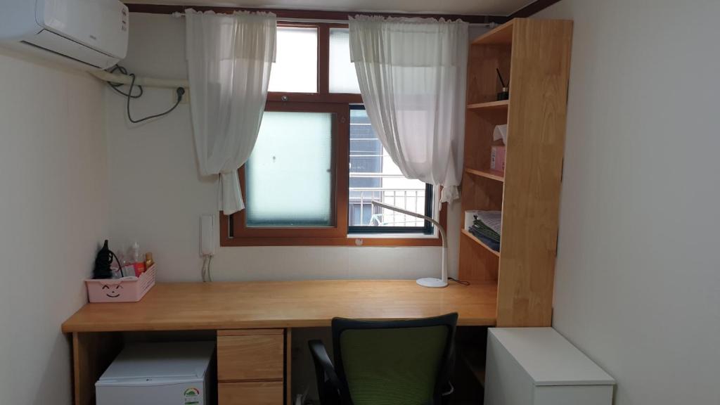 einen Schreibtisch in einem Zimmer mit Fenster in der Unterkunft dakwan stay in Seoul