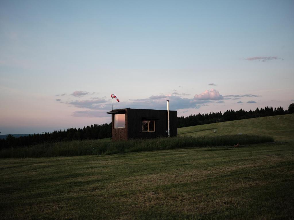 une petite maison sur une colline dans un champ dans l'établissement Hideandseek Aranka, domek s finskou saunou, à Hora Svaté Kateřiny