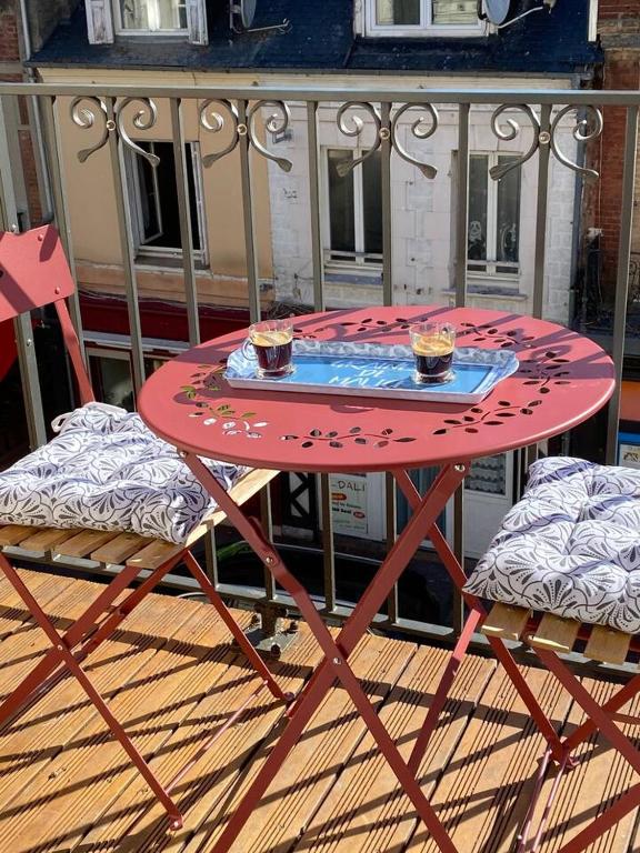 une table rouge et des chaises avec deux tasses dessus dans l'établissement Nid douillet Trouville sur mer, à Trouville-sur-Mer