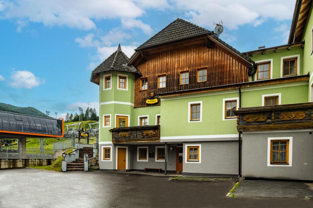 a large green building with a wooden roof at Waldschlössl Gasthof in Sankt Lorenzen ob Murau