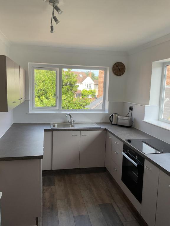 a white kitchen with a sink and a window at Large 2-bedroom maisonette with free parking in Twickenham