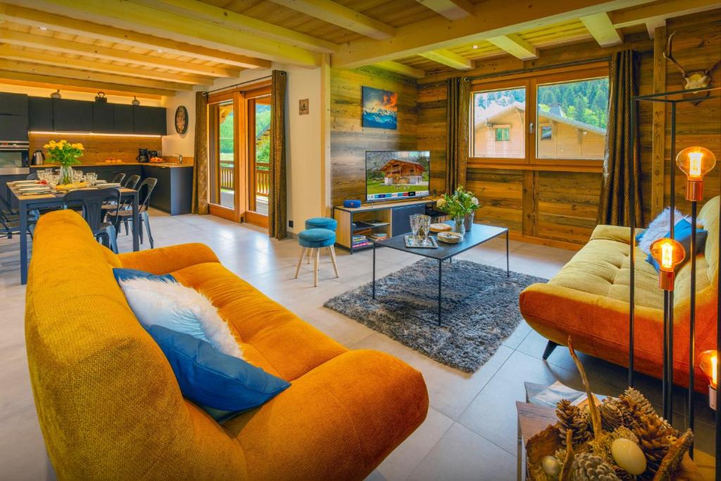 un salon avec un canapé orange et une table dans l'établissement Chalet Les Vardafes - OVO Network, à La Chapelle-dʼAbondance