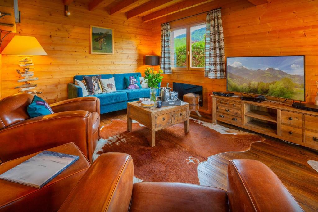 sala de estar con sofá azul y TV en Chalet Isatys - OVO Network, en Manigod