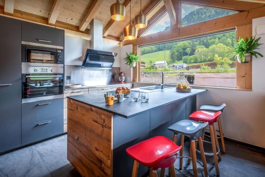 a kitchen with a large kitchen island with red stools at Chalet 65bis - OVO Network in Thônes