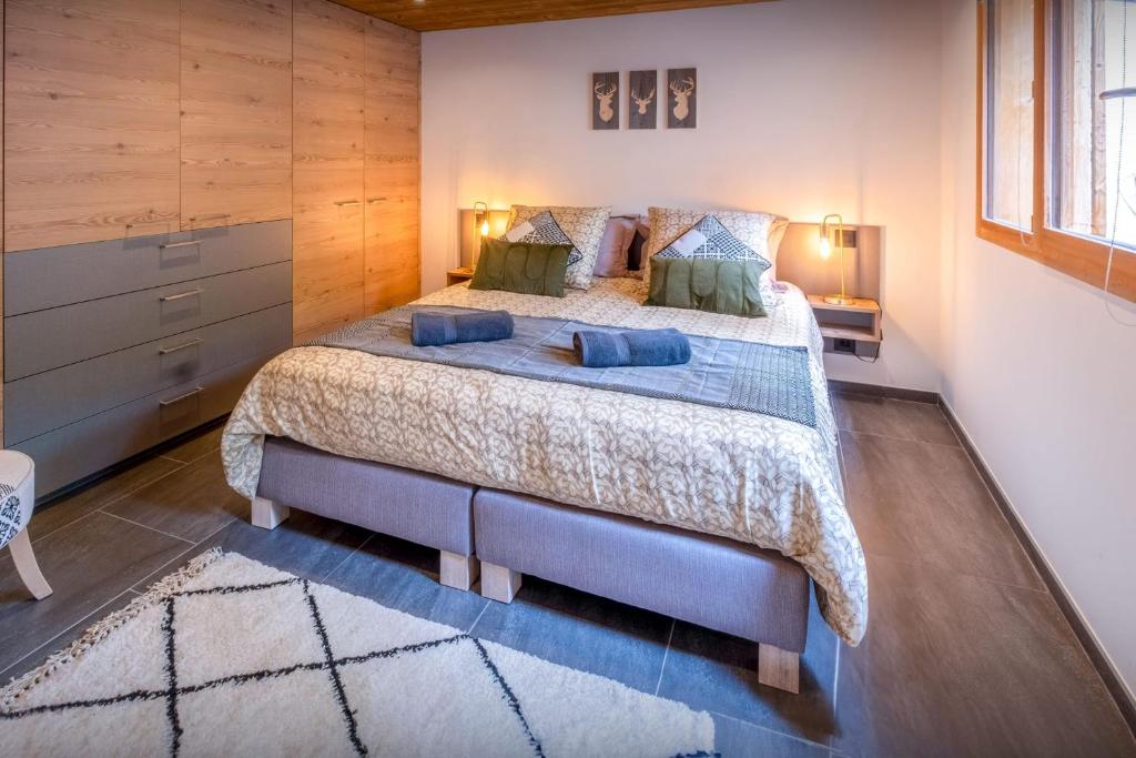 a bedroom with a large bed with blue pillows at Chalet 65bis - OVO Network in Thônes
