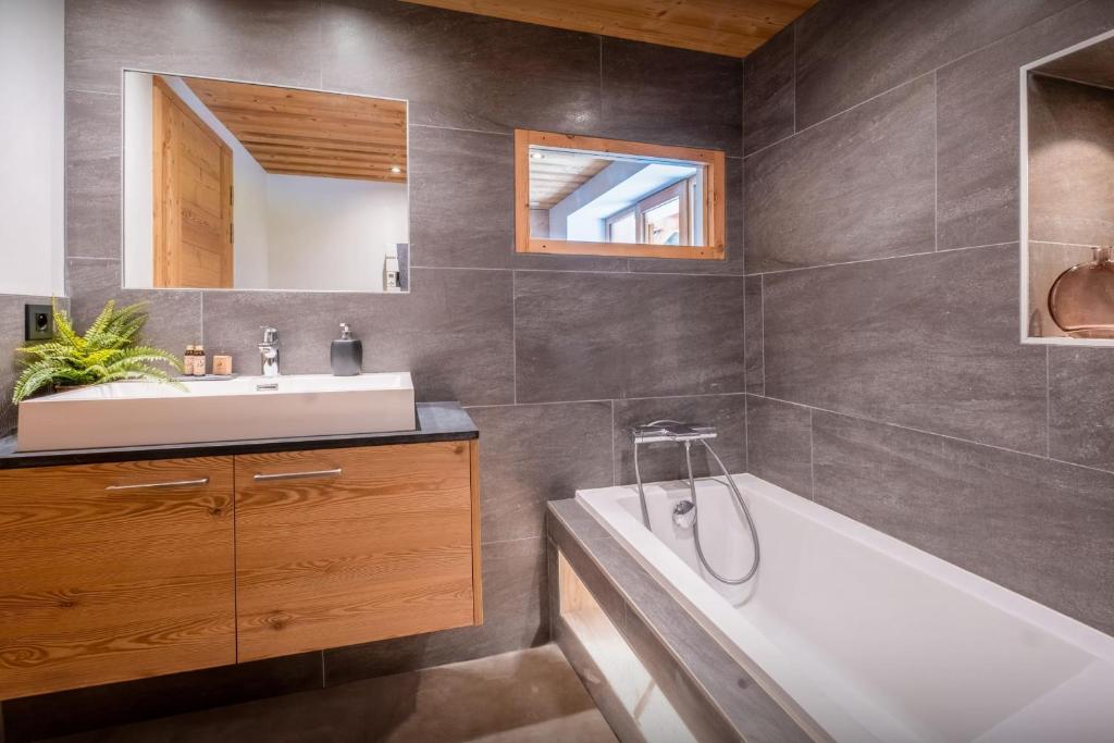 a bathroom with a tub and a sink and a mirror at Chalet 65bis - OVO Network in Thônes
