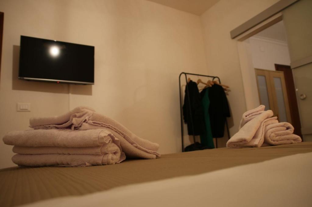 een slaapkamer met een bed met handdoeken en een flatscreen-tv bij Amira Apartments Trapani in Trapani