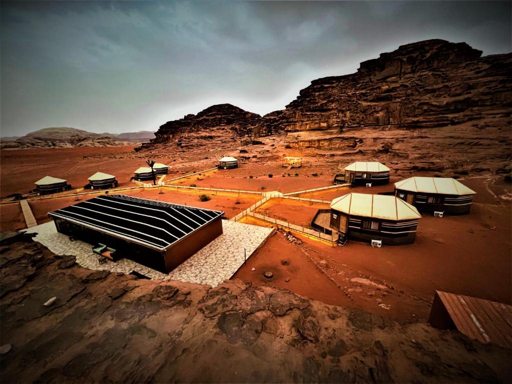 un groupe de bâtiments dans un désert avec une montagne dans l'établissement The Villas - Bedouin Boutique Resort, à Wadi Rum