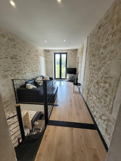 a living room with a couch and a stone wall at Appartement 2 pers + terrasse in Saint-Rémy-de-Provence