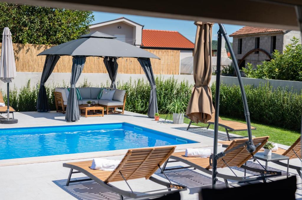 - une piscine avec des chaises et des parasols à côté dans l'établissement Villa Musulin, à Metković