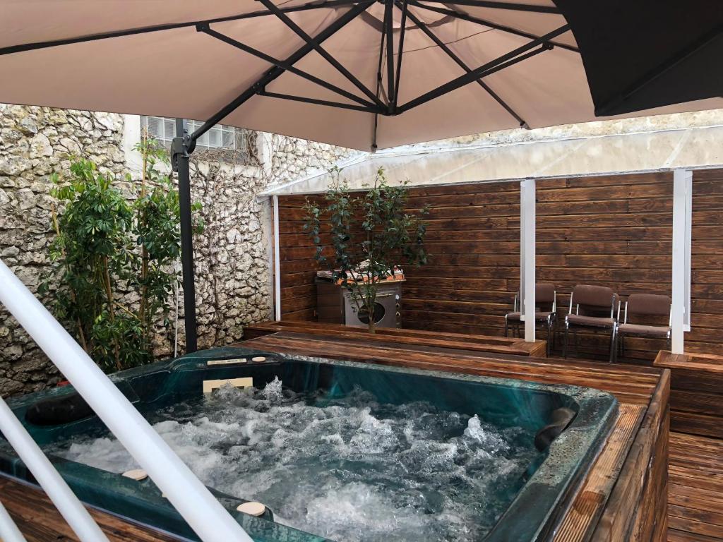 an outdoor hot tub with an umbrella on a deck at maison blanche in Eymet