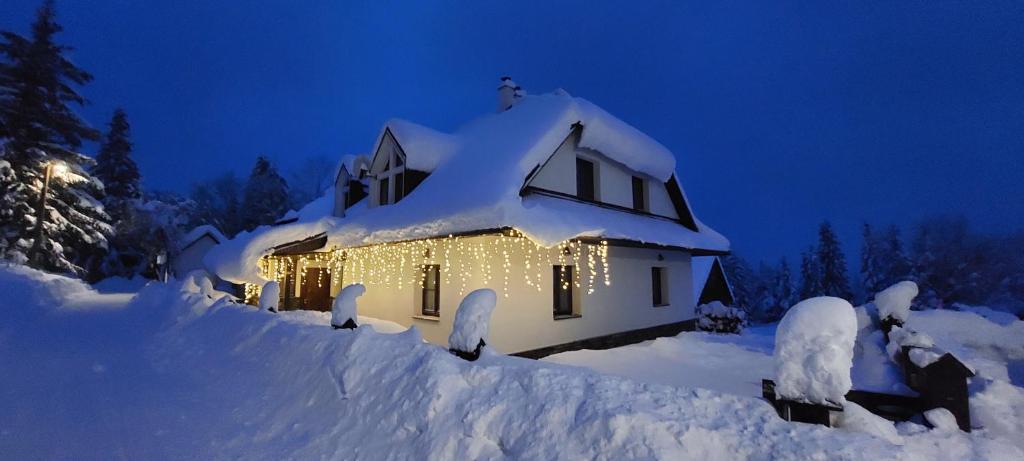 una casa cubierta de nieve con luces encendidas en Chaluba Bully 243, en Donovaly