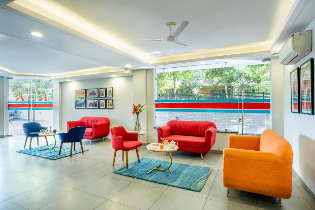 - une salle d'attente avec des chaises rouges et des chaises bleues dans l'établissement Inde Hotel Sec- 49, Golf Course Extension, Gurgaon, à Gurgaon