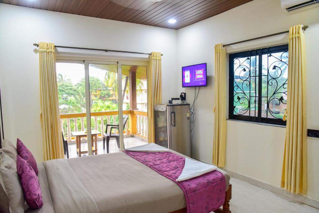 a bedroom with a bed and a window and a tv at ULTIMATE STAY in Calangute