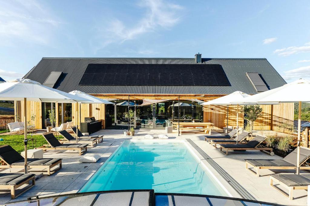 a swimming pool with lounge chairs and umbrellas at Premium Ferienhaus Das Farmhaus - Auf den Moselhöhen - Pool, Sauna, Kino, Garten in Lieg