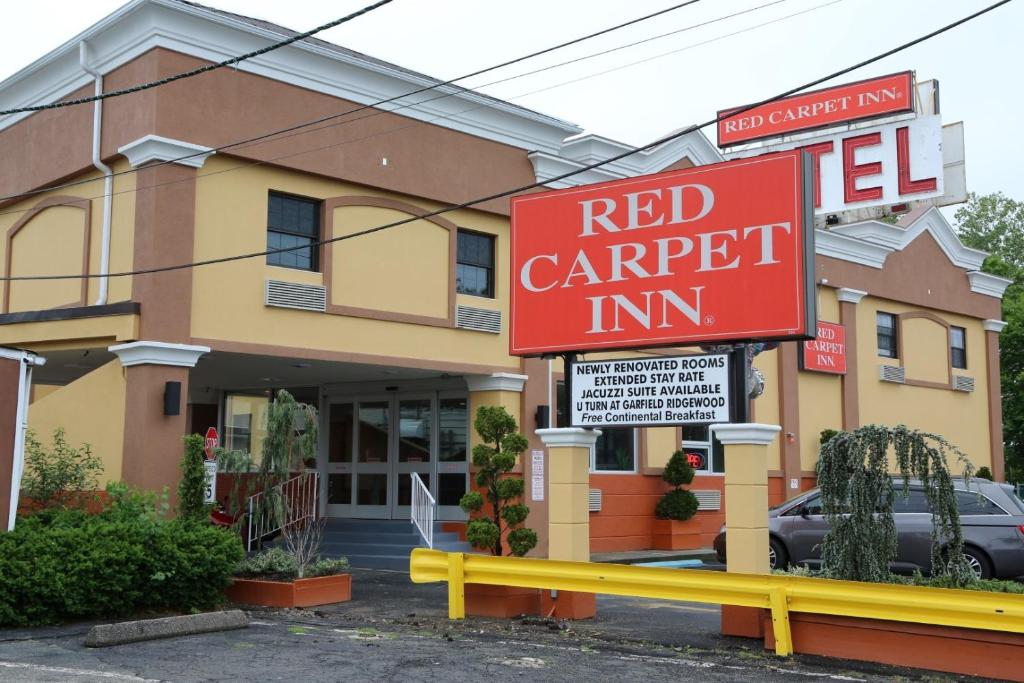 ein rotes Gasthofsschild vor einem Gebäude in der Unterkunft Red Carpet Inn Elmwood in Elmwood Park