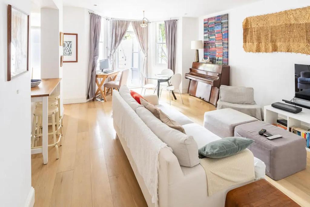 een woonkamer met een witte bank en een piano bij Superior 5* Kensington, London Flat + Free Wi-Fi in Londen