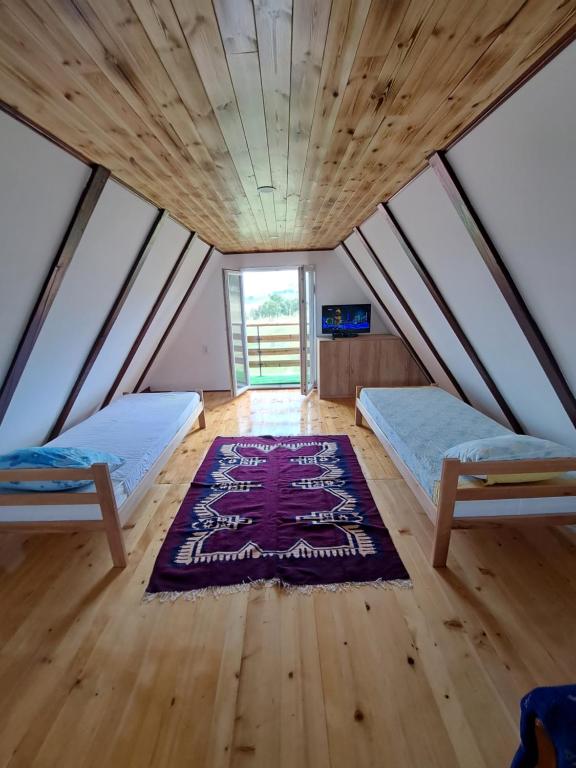 a room with two beds and a rug on the floor at Vikendica Velanac in Zlatibor