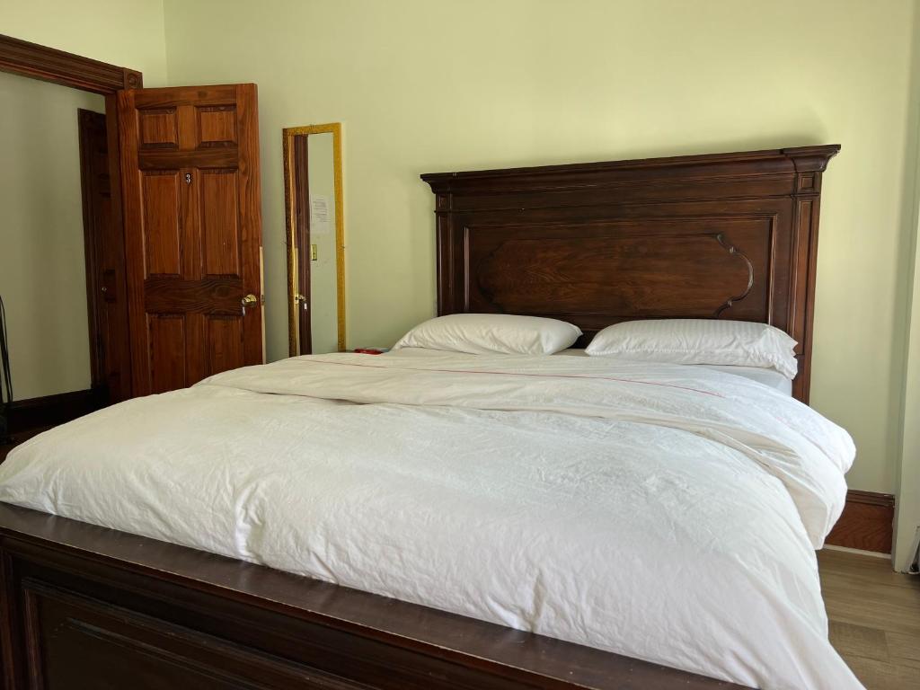 a large bed with a wooden headboard and white sheets at Malden rooms in Malden