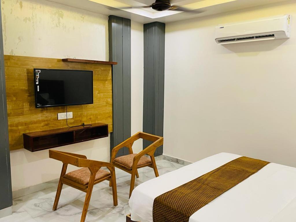 a bedroom with a bed and a tv and a chair at Hotel Fusion in Kurukshetra