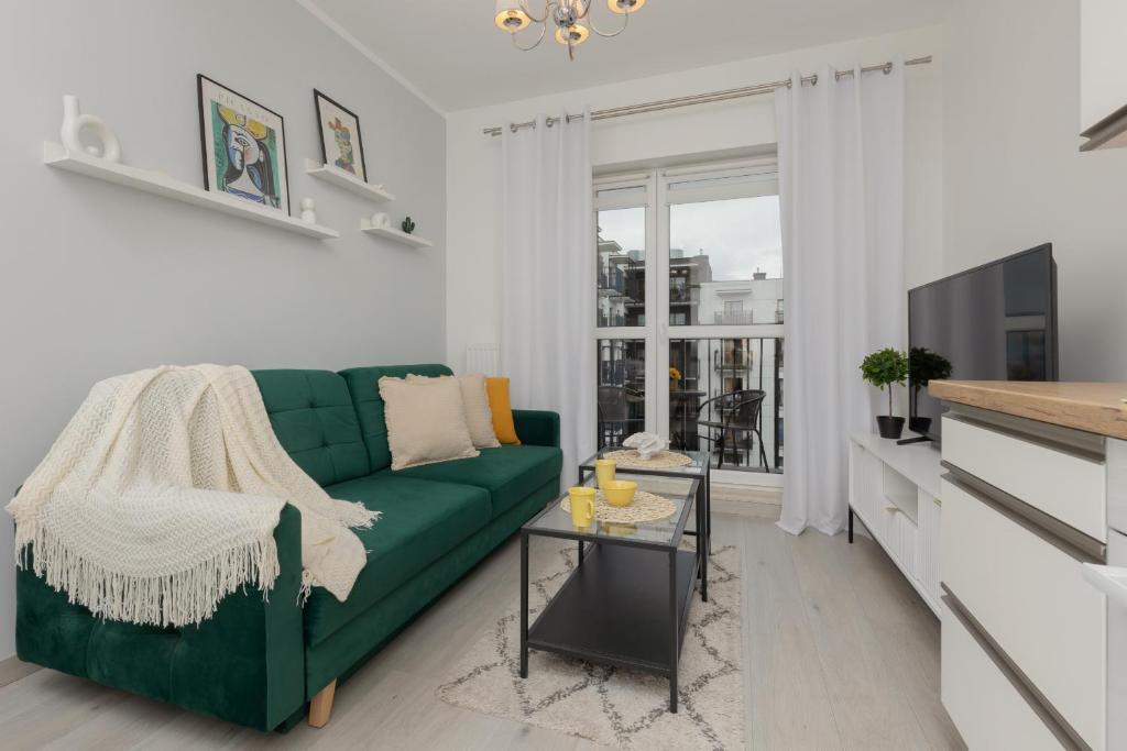 a living room with a green couch and a tv at Cozy Apartment with Parking Bakalarska by Renters in Warsaw