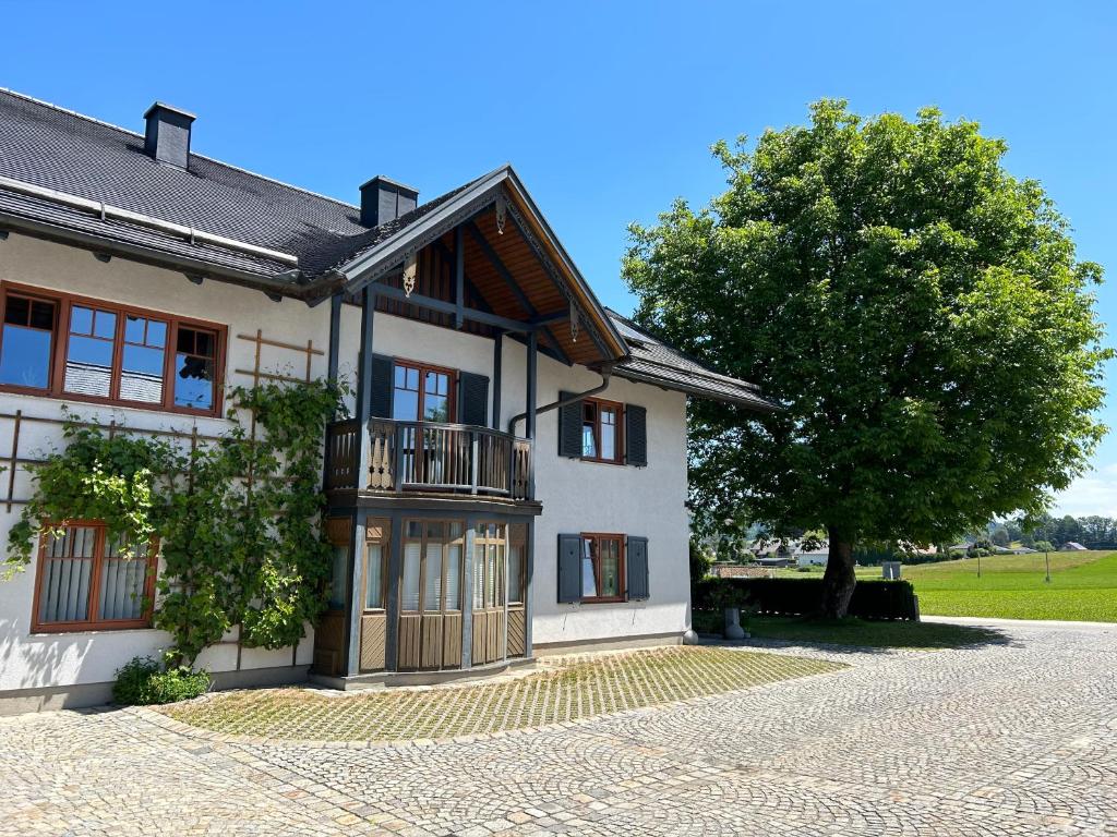 een wit huis met een boom ervoor bij Traumhaft große Ferienwohnung nähe Attersee in Sankt Georgen im Attergau